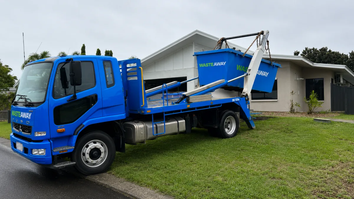 NT Waste Away truck delivering a blue skip bin beside a Darwin home